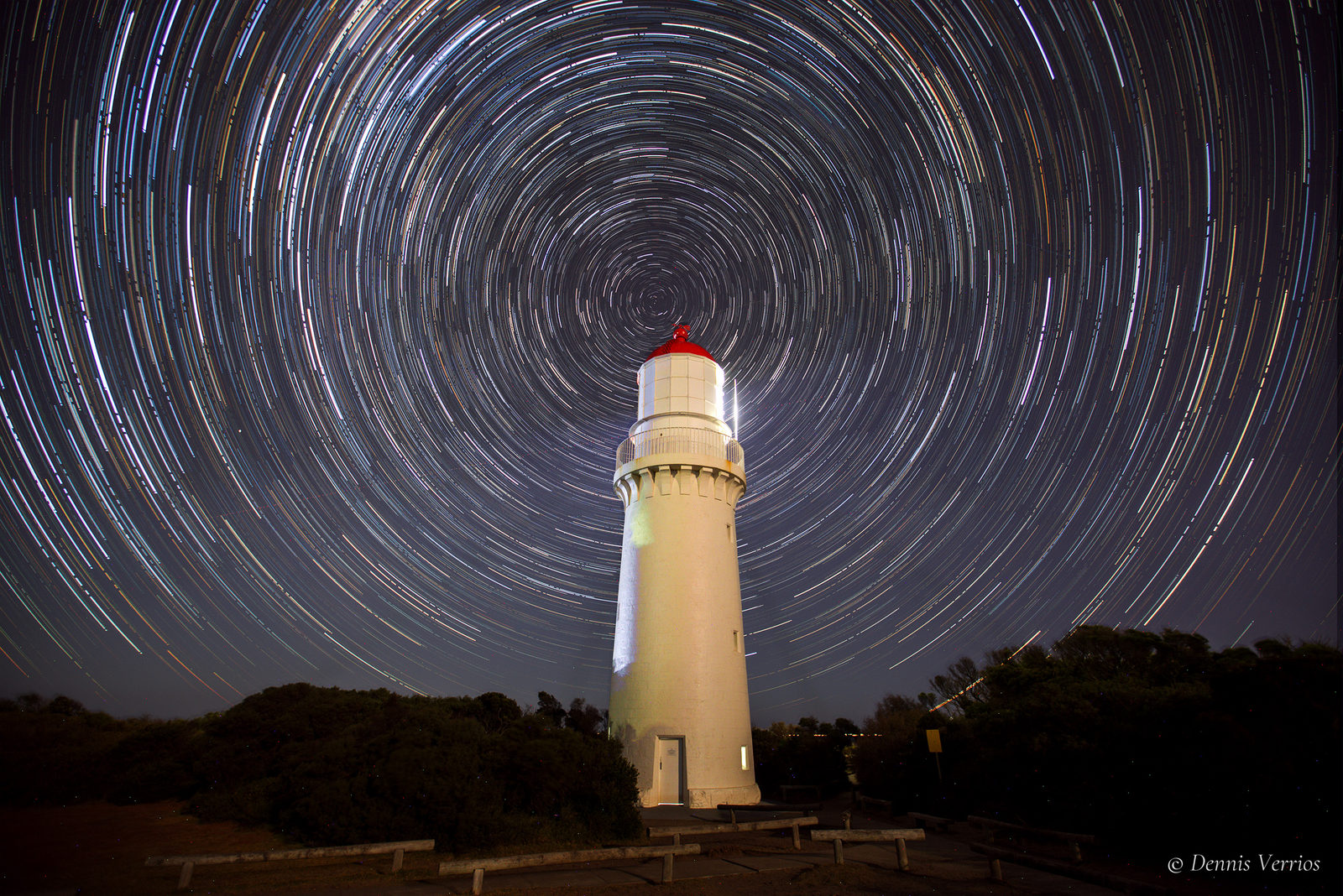 Circular star trails spinning around the south celestial pole directly above Cape Schanck Lighthouse at night. Photograph by Dennis Verrios.