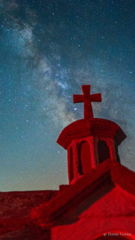 Red-lit roadside church and the Milky Way, portrait crop. Photograph by Dennis Verrios.
