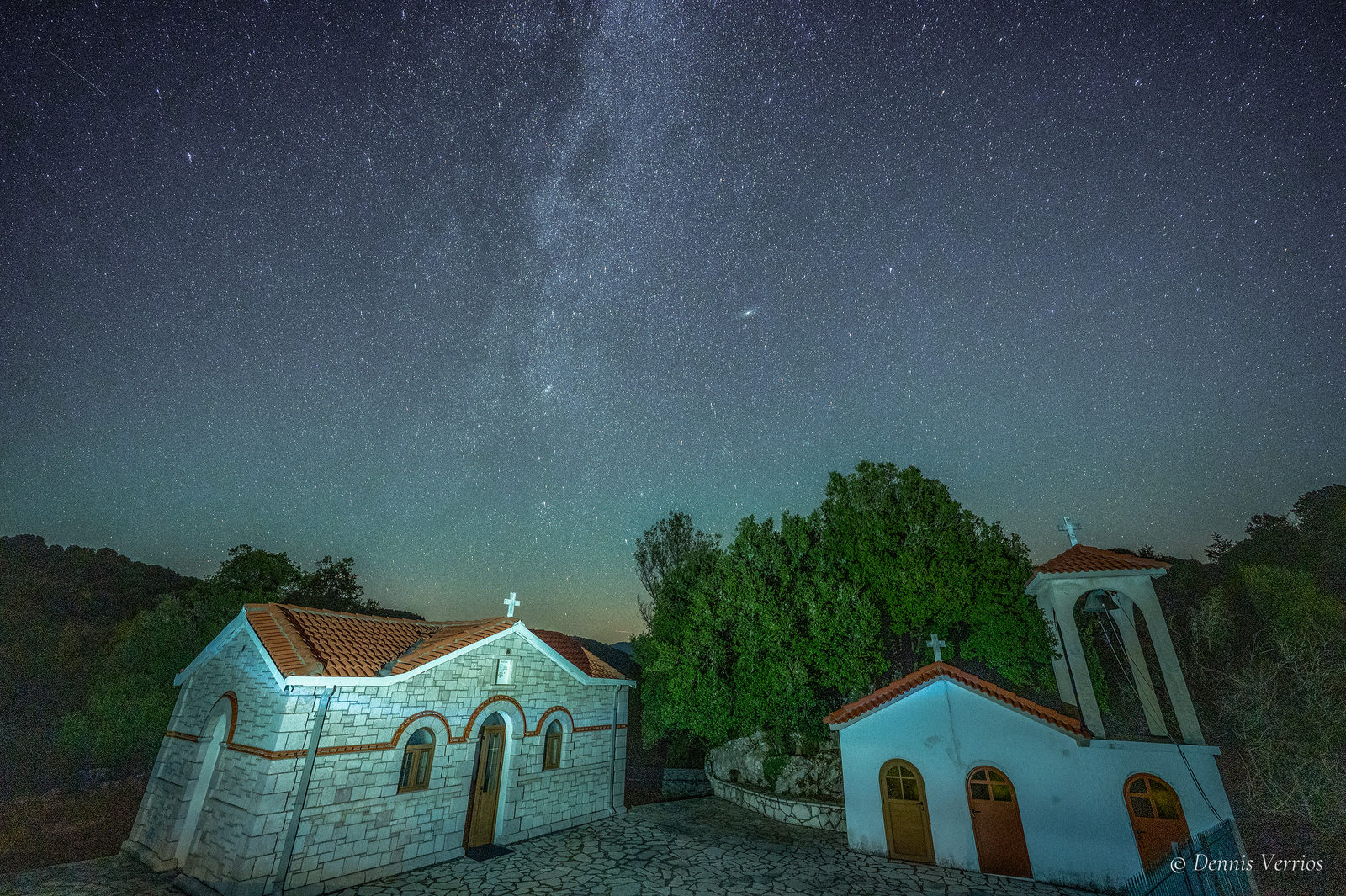 The Verrios family church in Valtesiniko, Arcadia, Greece: stone walls, terracotta roofs and a small bell tower under a starry sky with the Milky Way. Photograph by Dennis Verrios.